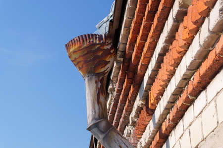 Rain gutters on old home. There is a blue sky in the background.