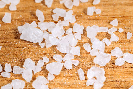 Sea salt falls on a wooden surface, close-up, macro.