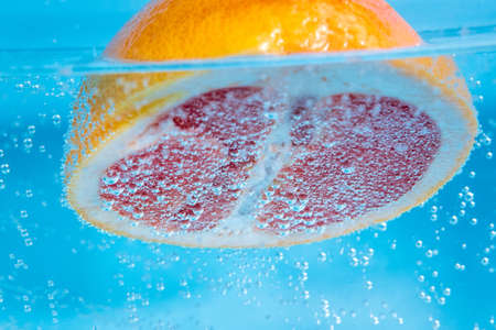 Grapefruit close up macro, under water, for juice. Ripe juicy fruit in water
