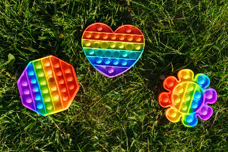 Toy pop it. Rainbow color. Antistress toy for children and adult. lying on the grass