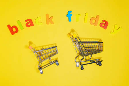 Shopping cart inscription black friday, copy space, yellow background. Shopping concept.