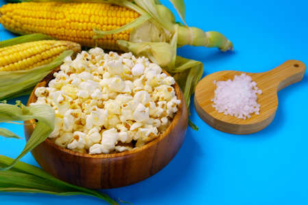Corn on the cob, popcorn on a blue background. Topic - agro, corn cultivation, harvest.