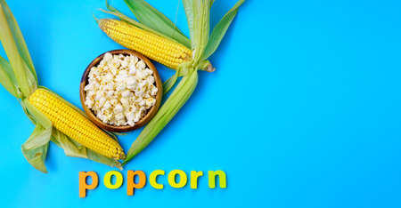 National Popcorn Day. Popcorn with corn cobs on a blue background. Copyspace
