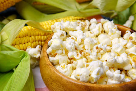 Homemade popcorn served in bowl together with raw corns. Close up