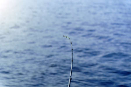 Fishing rod on a background of blue water, selective focus with copy space for text.の写真素材