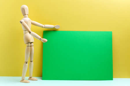 Wooden man presents empty space for your text copy. Green backgroundの写真素材