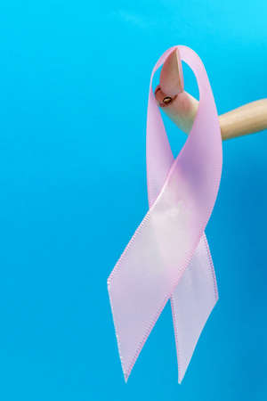 Pink ribbon and wooden mannequin. Health concept pink ribbon. Breast cancer. Vertical photo