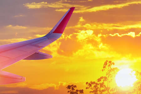 Wing of an airplane flying at sunset, morning time. The concept of the freedom journeyの写真素材