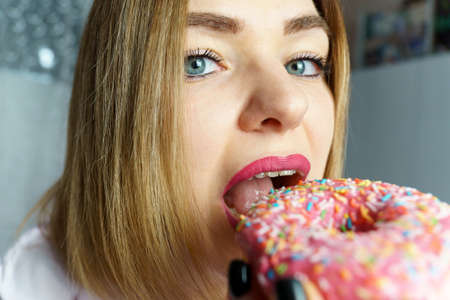 Portrait of a hungry young woman selective focus eating a donut. Wide angleの写真素材
