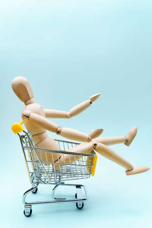 Mini shopping cart with wooden mannequin. advertisement for gift from all or composition concept. Copy Space. Vertical photoの写真素材