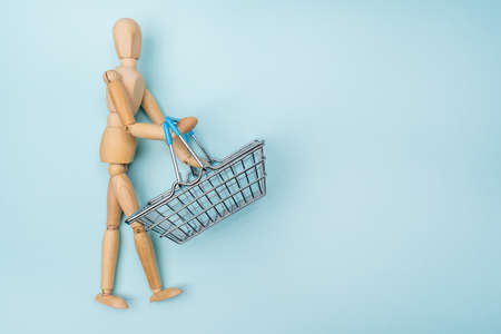 Mini shopping basket with wooden mannequin. advertisement for gift from all or composition concept. Copy spaceの写真素材
