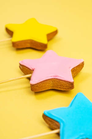 Multicolored cookies on sticks on a yellow background Cake decorating tools. Confectionery concept. Top view. Vertical photoの写真素材
