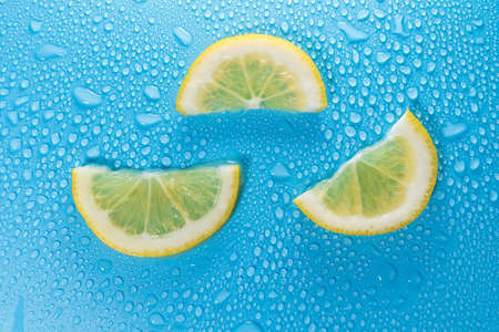 Lemon slices on a blue background with water drops. Background textureの写真素材