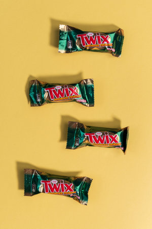 Tyumen, Russia-January 23, 2022: Twix Minis with the taste of ginger cookies candy bars lies on yellow background. Vertical photoのeditorial素材