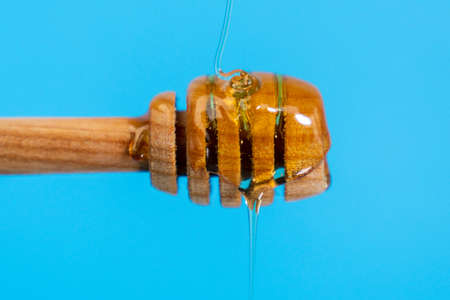 Dripping honey blue background from a wooden spoon. copy spaceの写真素材