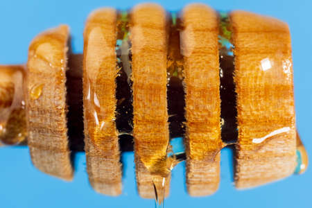 Healthy organic Thick honey dripping from the wooden honey spoon, closeup, macro