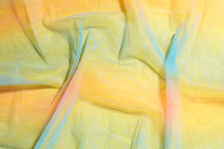 Rainbow yellow fabric background. Silk fabric in iridescent colors creates folds. Multicolored...