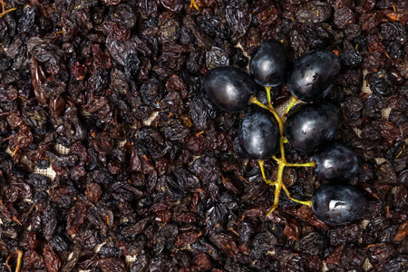 Black raisins with grapes on a wooden background, healthy snack, dietary product.の写真素材