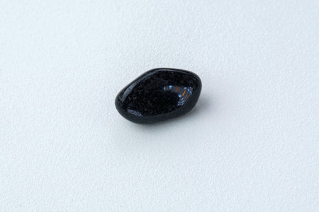 Close up of natural mineral from geological collection tumbled black onyx gem stone, white...