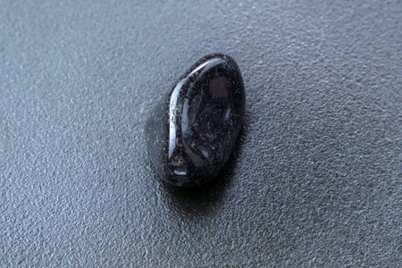 Close up of natural mineral from geological collection tumbled black onyx gem stone, black backgroundの写真素材