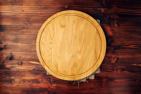 Empty round kitchen board on a wooden background, an empty copy spaceの写真素材