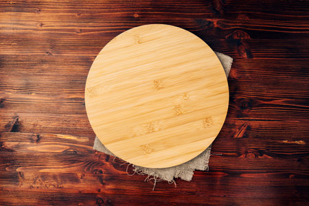 Round cutting board on a wooden kitchen table. Free space for your decorationの写真素材