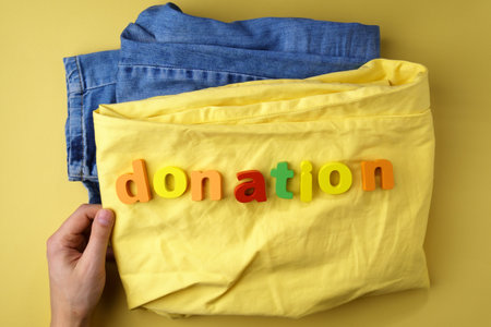 Jeans with the inscription donation, concept of helping people in need. Give to charity, yellow backgroundの写真素材