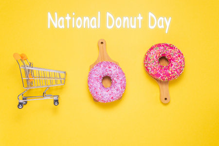 National Donut Day, donuts with pink sugar glaze and sprinkled with colorful pastry crumbs, on a yellow background.の写真素材