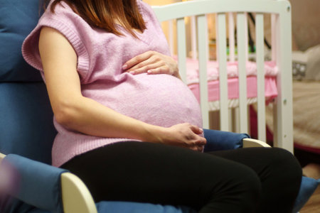 Woman is holding her stomach while sitting in a chair. A pregnant woman is expecting a babyの写真素材