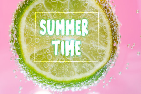 Summer, highlighted by the effervescent bubbles clinging to a submerged lime slice surrounded by a...