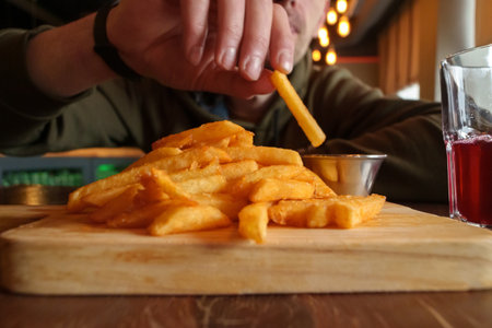 Crispy French fries arranged neatly on a wooden cutting board, showing their golden color and crispy...