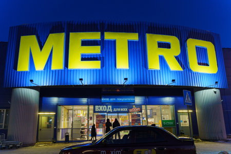 Tyumen, Russia-March 02, 2024: Metro sign glows brightly, with the silhouettes of city buildings in...