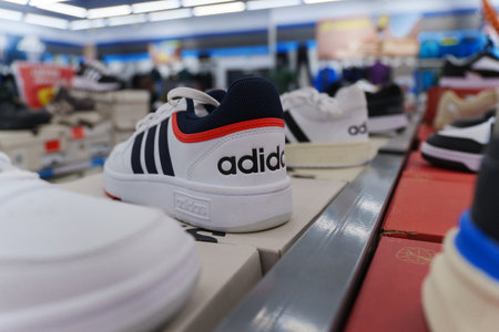Tyumen, Russia-August 11, 2024: White athletic shoes adidas with black stripes is showcased prominently in a retail environment.のeditorial素材