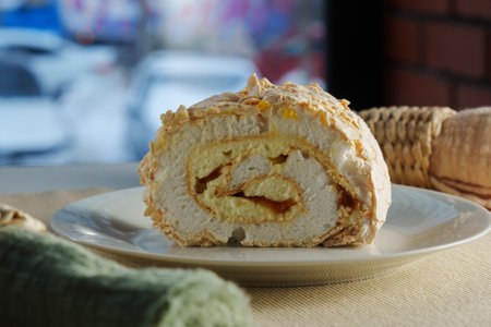 A beautifully crafted dessert roll sits elegantly on a plate, revealing layers of cream and sweet filling, complemented by a lively urban backdrop.の写真素材