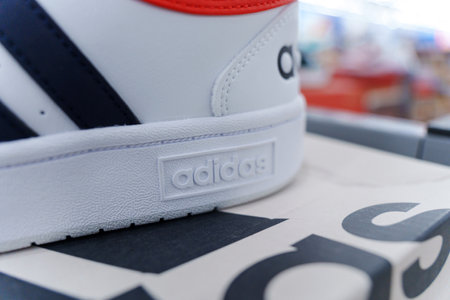 Tyumen, Russia-August 11, 2024: White athletic shoes adidas with black stripes is showcased...