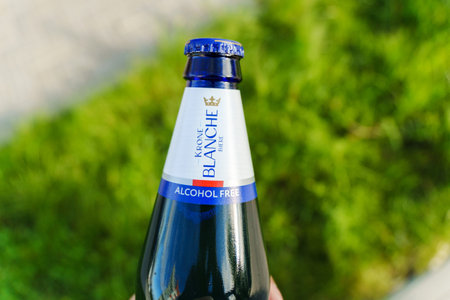 Tyumen, Russia-August 10, 2024: A person holding a bottle of alcohol-free Krone Blanche on a swing in a park during daylightのeditorial素材
