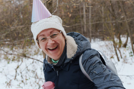 A bright smile lights up the snowy landscape as a person wearing a festive hat enjoys a cheerful...