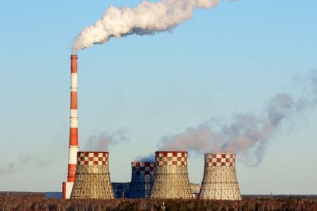 A large power plant features cooling towers emitting steam into the clear blue sky.の写真素材