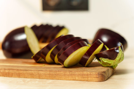 Slicing fresh eggplant on a wooden cutting board in a contemporary kitchen setting