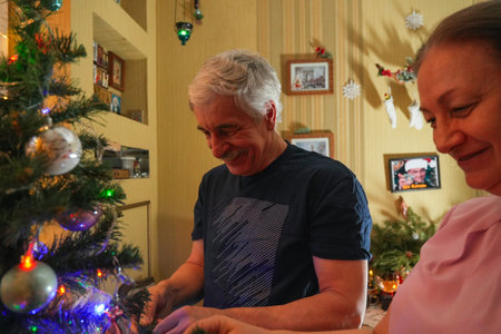 Couple decorating a Christmas tree at home while enjoying festive moments together in Decemberの写真素材