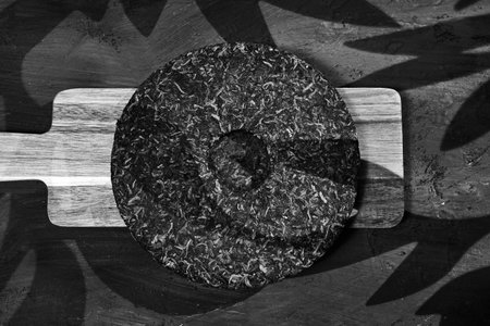 Puer tea resting on a wooden board with light shadows creating an elegant displayの写真素材