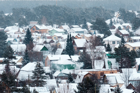 Winter envelops a tranquil village with snow-covered rooftops and quiet streets amidst a frosty landscapeの写真素材