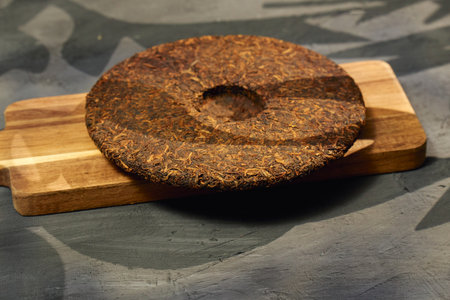Puer tea rests on a wooden cutting board, showing its rich texture and earthy color.