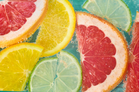 Fresh citrus fruits in sparkling water create a refreshing summer drink experience with vibrant...