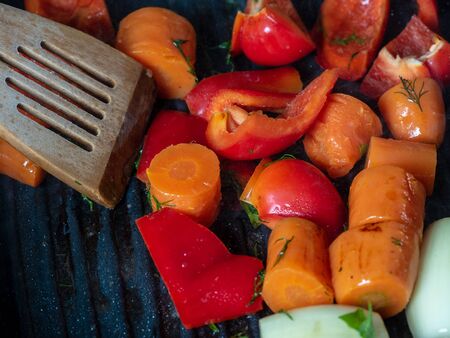 Fresh vegetables are cooked in a pan-grill. Carrots, sweet red peppers, onions. Concept of vegetarian and healthy food.の写真素材