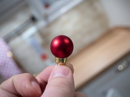 A man holds a small decorative red ball in his hand. The concept of new year and Christmas
