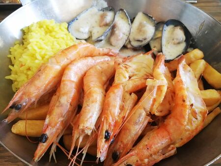 Mediterranean dishes of fried shrimp mussels in a sauce garnished with riceの写真素材
