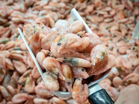 close up of fresh pink frozen shrimp covered in ice in metal scoop in fish shop.の写真素材