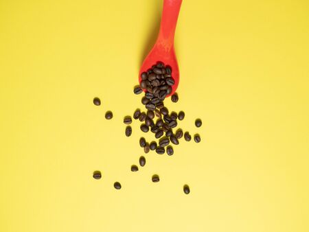 roasted coffee beans falling down from metal scoop isolated on white