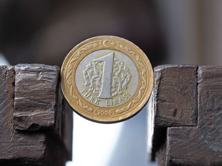 Coin one Turkish Lira clamped in a vise. The concept of financial and economic problems.
